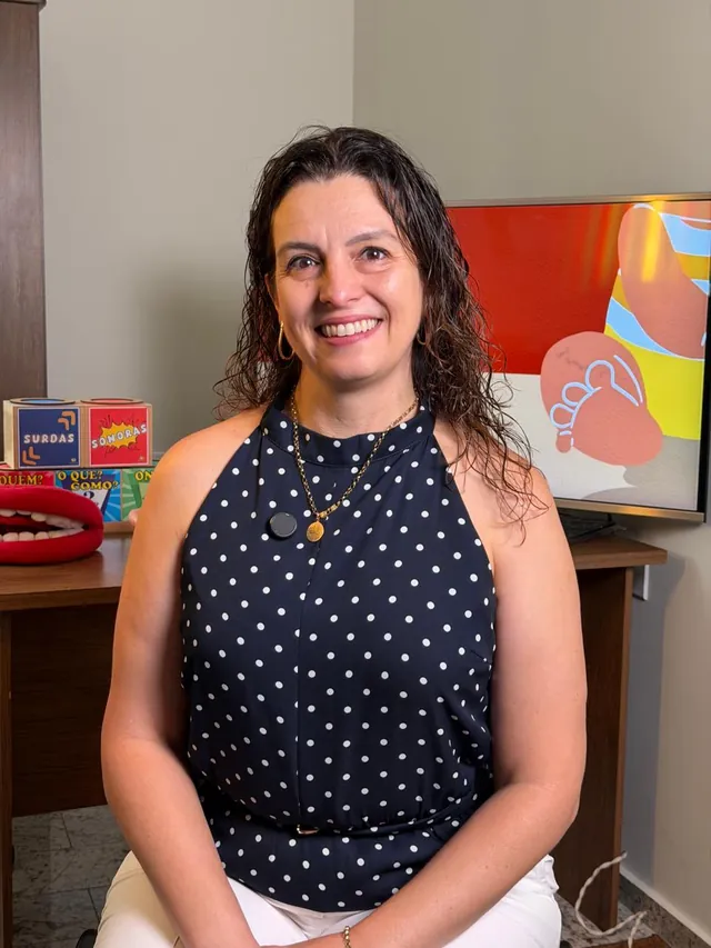 Rosane no consultório, com materiais de terapia ao fundo